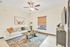 Cozy living room with stylish decor, featuring a plush sectional sofa, modern ceiling fan, and a chic wooden coffee table on a patterned rug, perfect for relaxation.