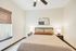Bright and inviting bedroom featuring a cozy bed with soft lighting, complemented by elegant decor and natural light filtering through a stylish window shade.