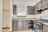 Charming kitchen featuring sleek dark cabinets, granite countertops, and a modern stove, flooded with natural light through a window with blinds.