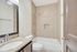 Modern bathroom featuring elegant granite countertops, a sleek vanity mirror, and a pristine bathtub with contemporary tile surround.