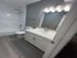 Modern bathroom with sleek white fixtures, elegant lighting, and hardwood flooring.