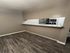 Chic apartment kitchen with sleek laminate flooring, modern stainless steel appliances, and an inviting breakfast bar area.