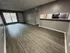 Inviting open-plan living area with chic wood flooring and modern kitchen pass-through, bathed in natural light.