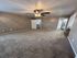 Inviting bedroom with plush carpet, modern ceiling fan, ample closet space, and neutral-tone walls for a warm and cozy atmosphere.