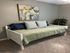 Cozy bedroom featuring a stylish daybed with plush pillows, elegant abstract artwork, and lush green indoor plant for a serene ambiance.