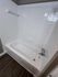 Modern bathroom with a sleek white bathtub, elegant tile surround, and stylish dark wood flooring.