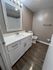 Chic bathroom with modern fixtures, featuring sleek white vanity, elegant mirror, and rich wood-look flooring.