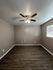 Modern bedroom with sleek dark wood flooring, neutral walls, and a stylish ceiling fan illuminating the space.