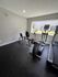 Cardio workout area at Trailwood Village Apartments in Kingwood, Texas, featuring an elliptical trainer, recumbent bikes, and a treadmill by a large window.