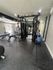 Modern fitness center at Trailwood Village Apartments in Kingwood, Texas, featuring a dual-pulley cable machine, weight benches, and exercise balls.