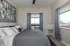 Stylish bedroom featuring a modern gray color scheme, contemporary art piece, and city view through large windows.