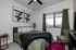Chic bedroom with modern decor, green bedspread, stylish artwork, and a window view.