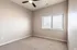 Spacious bedroom with neutral walls, plush carpeting, and a ceiling fan with a window view.