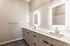 Contemporary bathroom with a double sink, stylish wooden cabinetry, and illuminated mirrors.