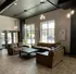 Modern lounge area with chic brown leather sofas, large windows for natural light, and contemporary geometric artwork on gray walls.
