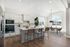 Bright, modern kitchen and dining area with sleek countertops, elegant cabinetry, and a stylish island bar. Large windows bathe the space in natural light, highlighting the chic design and inviting atmosphere.