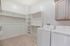Spacious walk-in laundry room with ample storage space, featuring a modern washer and dryer set alongside elegant cabinetry.