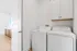 Modern laundry room with sleek washing and drying machines, elegant cabinetry, and a bright, open layout.