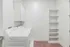 Modern laundry room with a sleek washer and dryer, white cabinetry, and spacious shelving.