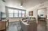College Town, interior, living room, gray sofa and arm chair, coffee table, large windows, tv, doorway to bedroom, desk, chair, computer