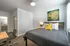 College Town, bedroom, bed, gray comforter, desk, chair, wall art, doorway to bathroom
