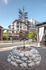 College Town, exterior, tall torch with feathers, planted in a large stone surround, buildings and tree in the back,