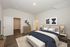 Spacious bedroom with modern decor, featuring a cozy bed, stylish artwork, and wooden flooring.