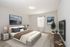 Spacious bedroom with modern decor, featuring a large bed, plush pillows, and serene artwork.