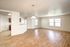 Spacious open-concept living area with natural light, featuring elegant wood flooring and a cozy kitchen space.