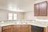 Modern kitchen with sleek granite countertops, double sink, and rich wooden cabinets complemented by natural light.
