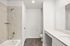 Bright and modern bathroom with elegant tile bathtub, sleek vanity, and contemporary wood flooring.
