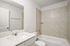 Contemporary bathroom boasting a sleek vanity, polished fixtures, and a classic tiled bathtub.