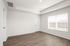 Bright and spacious room with large window, presenting natural light and modern wood flooring.