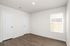 Bright room with elegant hardwood floors and ample natural light from a large window, perfect for a cozy bedroom or office space.