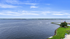Captivating lakeside view with lush greenery and a clear blue sky, perfect for serene living.