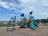 Charming playground with vibrant slides and climbing structures, surrounded by a scenic neighborhood backdrop.
