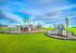 Vibrant playground set in a lush green park with modern climbing structures under a bright blue sky.