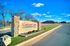 Inviting entrance to Crimson Lake Estates featuring a beautifully crafted stone sign and expansive blue sky, perfect for serene living.