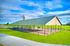 Charming outdoor pavilion with a metal roof, surrounded by lush green grass and a scenic backdrop, ideal for gatherings.