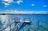 Serene lakeside view with a wooden dock under a vibrant blue sky.