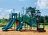 Charming outdoor playground with vibrant slides and climbing structures, surrounded by lush greenery and clear blue skies.