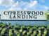 Inviting entrance sign of Cypresswood Landing with vibrant landscaping and clear blue sky.