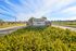 Welcoming entrance to Enchanted Bay with vibrant yellow flowers and well-maintained landscaping, set against a backdrop of clear blue skies.