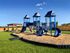 Inviting outdoor playground with bright blue slides, climbing structures, and lush green grass under a clear blue sky.