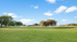 Expansive lush green park under a bright blue sky with scattered clouds, perfect for tranquil outdoor living in a vibrant community.