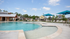 Luxurious outdoor pool area featuring crystal-clear water, sun loungers, and stylish blue umbrellas, perfect for relaxation and leisure.