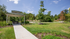 Charming outdoor picnic area with a covered pavilion surrounded by lush greenery and scenic trees under a clear blue sky.