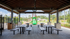 Inviting community area with covered seating and a vibrant green playground, surrounded by lush trees and homes.