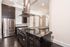 Modern kitchen with sleek stainless steel appliances, dark cabinetry, and elegant pendant lighting in an open-concept layout.