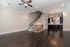 Elegant open-concept living area with dark hardwood floors, modern kitchen, and sleek staircase leading upstairs.